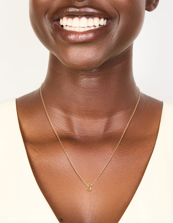Featuring a gold plated sterling silver letter S necklace with initials on neck view