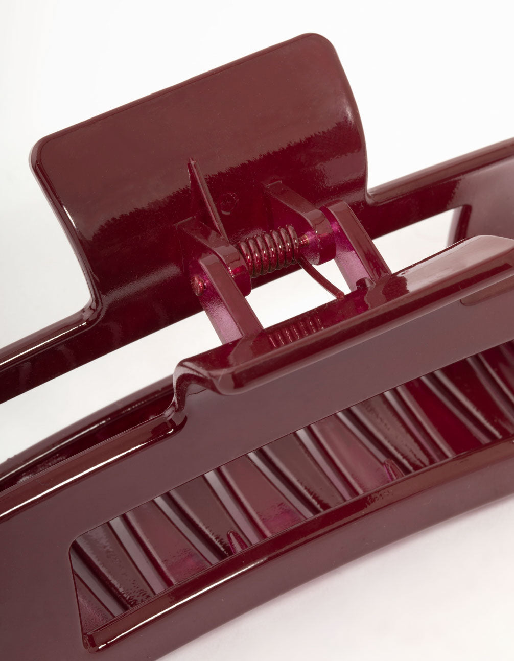 Crafted from shiny material, this large burgundy coated claw clip in maroon detail view