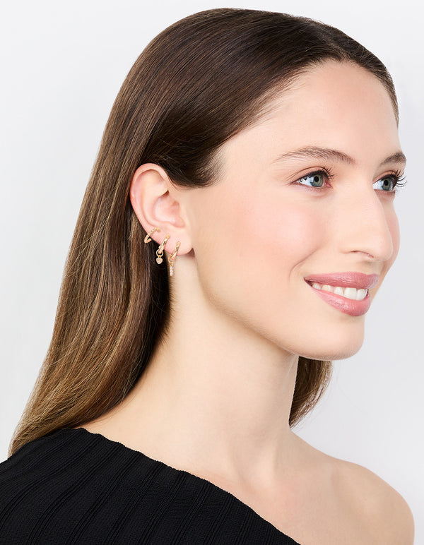 Crafted with gold cubic zirconia heart and twisted huggie earrings in a 3-pack with bar and charm elements on model view