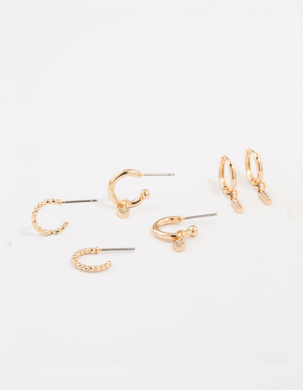 Showcasing gold cubic zirconia heart and twisted huggie earrings in a 3-pack with bar and charm details front view