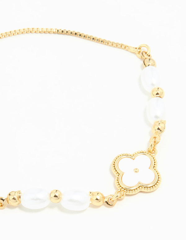 Showcasing a gold plated pearl flower toggle bracelet featuring beads, charm elements, and white accents close up view