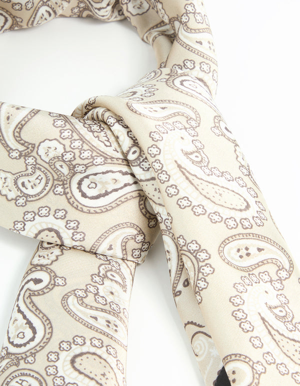 Detailed close-up of fabric scarf featuring paisley print in beige, tan, and black detail view