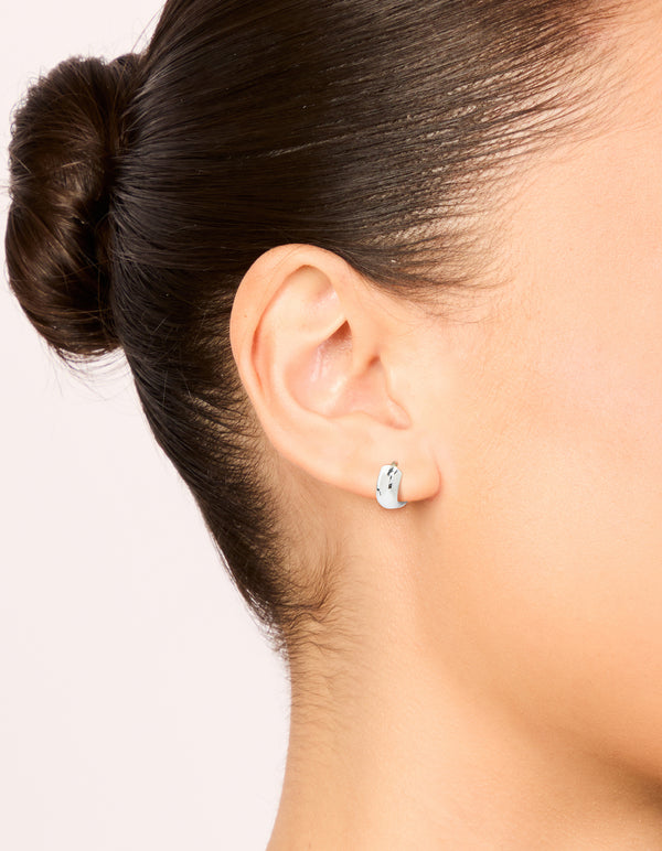 Featuring chunky waterproof stainless steel huggie earrings in silver on ear view