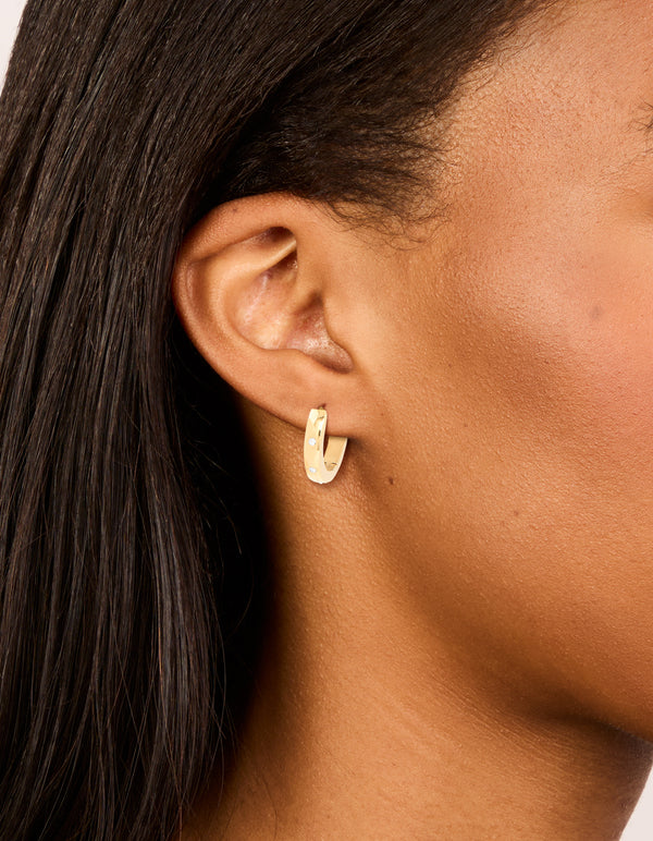 Showcasing waterproof gold plated stainless steel cubic zirconia trio huggie earrings with clear accents on ear view