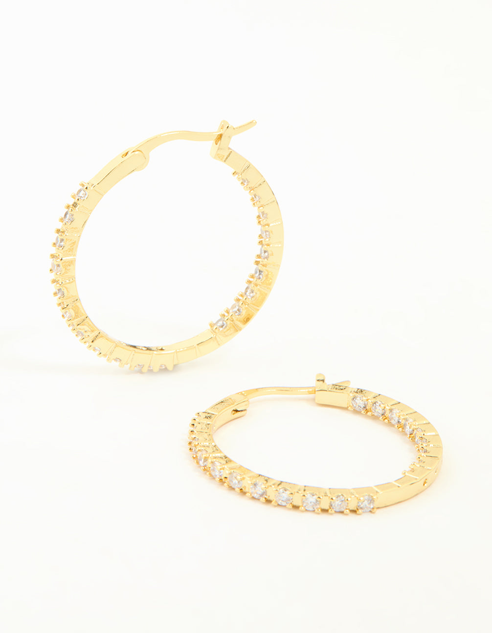 Showcasing statement large skinny hoop earrings in gold plated finish featuring cubic zirconia stones front view