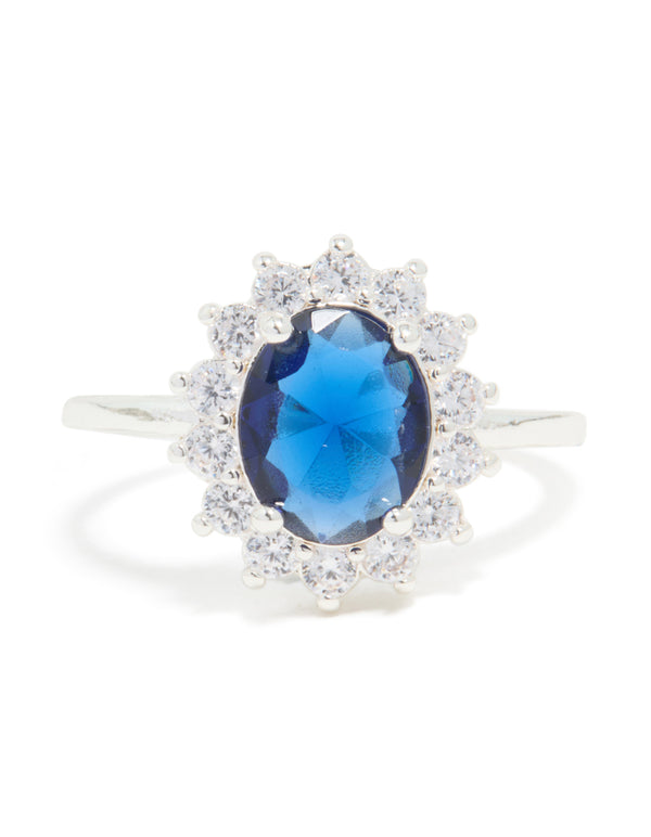 Showcasing a statement ring crafted from plated metal with an oval cut blue cubic zirconia center stone surrounded by crystal border front view
