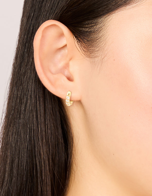 Featuring waterproof gold plated stainless steel huggie earrings with cubic zirconia on ear view