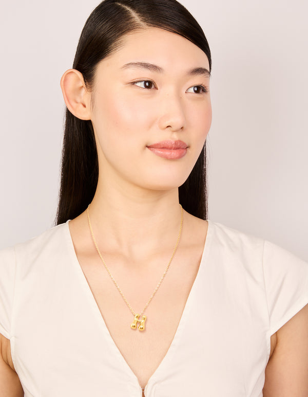 Displaying a waterproof gold plated stainless steel bubble letter H initial pendant necklace on model view