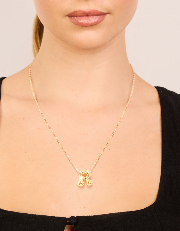 Showcasing a waterproof bubble letter R initial pendant necklace in gold plated stainless steel on neck view