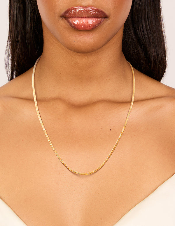 Displaying a waterproof snake short necklace crafted from stainless steel with dainty style in gold plated finish on neck view