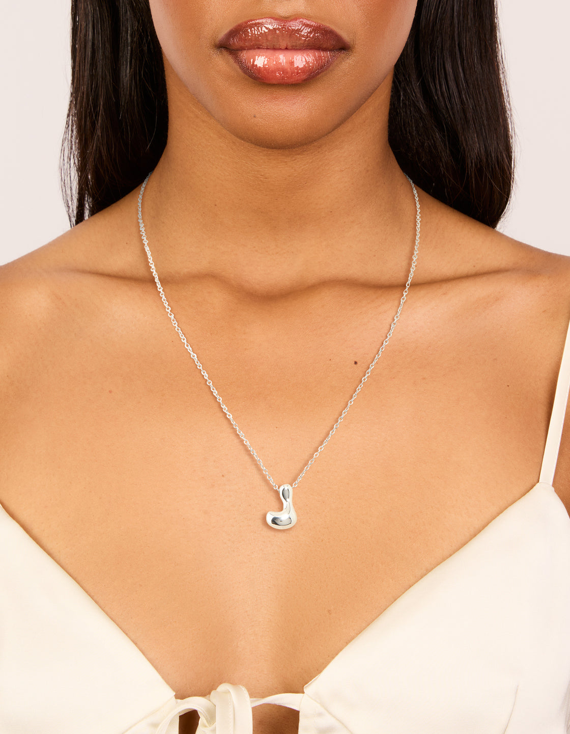 Featuring a waterproof stainless steel large bubble letter L necklace with initial pendant in silver on neck view