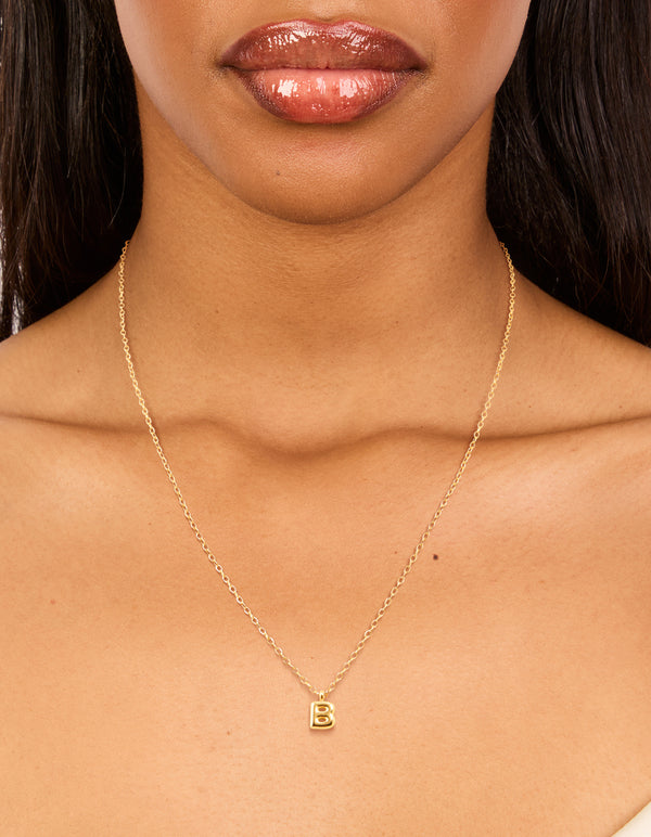 Showcasing a waterproof mini bubble letter B initial pendant necklace in gold plated stainless steel on neck view