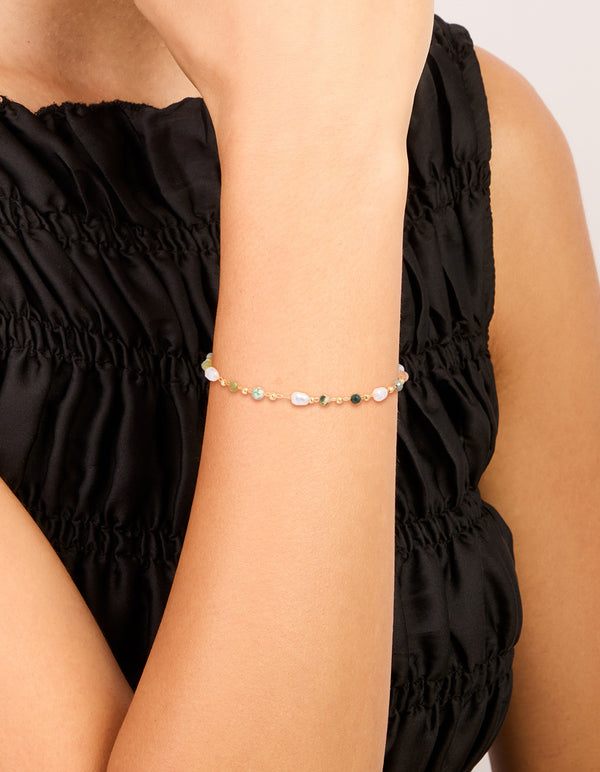 Showcasing a gold plated bracelet with green beads and pearls on wrist view