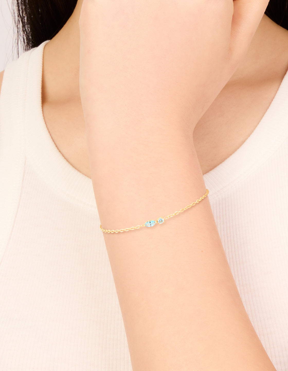 Showcasing a waterproof bracelet crafted from gold plated stainless steel featuring light blue cubic zirconia on wrist view