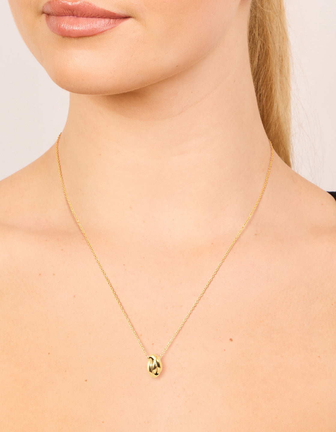 Showcasing a waterproof looped pendant necklace crafted from gold plated stainless steel on neck view