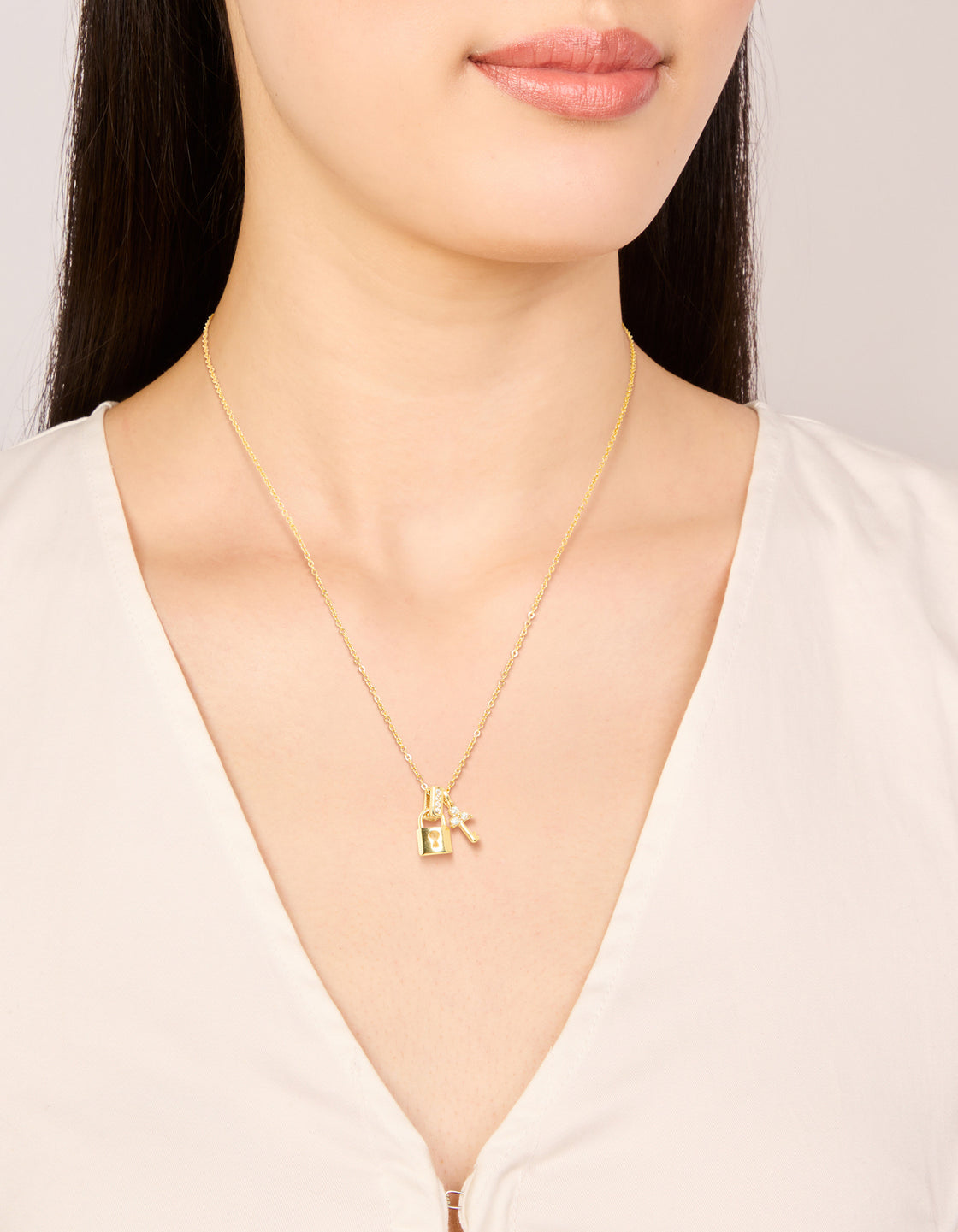 Featuring a waterproof charm padlock dainty lock and key necklace in stainless steel with cubic zirconia detailing shown in an on neck view