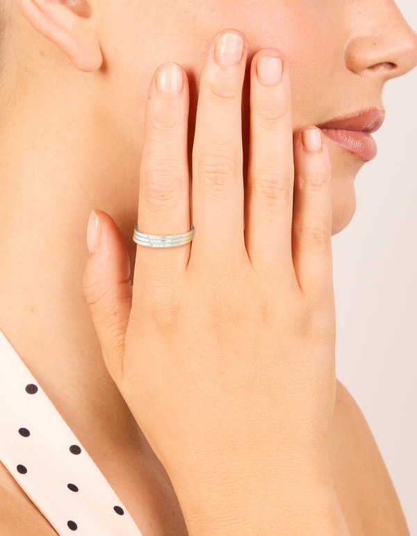 Crafted from waterproof stainless steel, these thin cubic zirconia trio rings in silver and clear stone are shown in a 3-pack on finger view