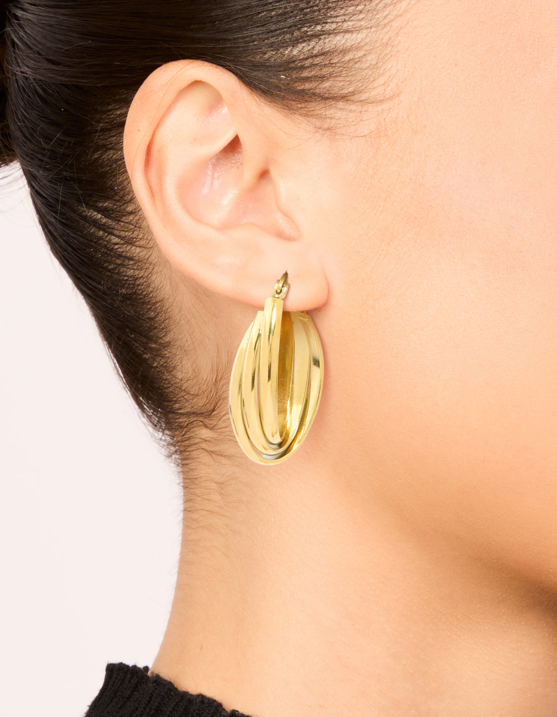 Showcasing waterproof gold plated stainless steel layered huggie earrings worn for scale and fit on ear view