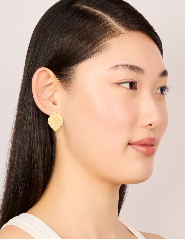 Designed with waterproof gold plated stainless steel textured leaf earrings in gold on model view