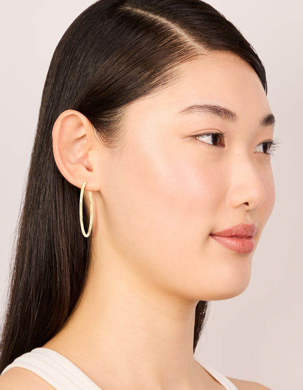 Featuring waterproof gold plated stainless steel statement hoop earrings on model view