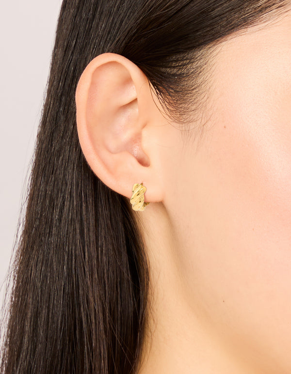 Crafted from waterproof gold plated stainless steel plaited detail huggie earrings on ear view