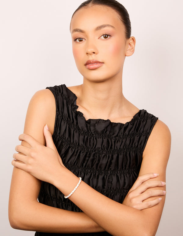 Featuring a waterproof bamboo bangle crafted from gold plated stainless steel with white enamel on model view