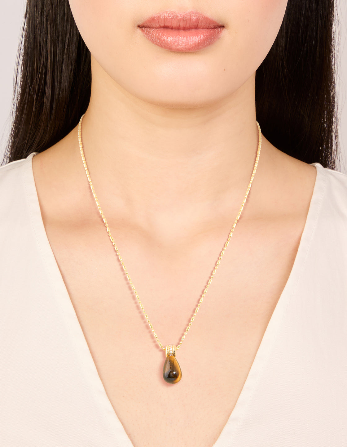 Showcasing a waterproof tiger eye semi precious stone pendant necklace in gold plated stainless steel on neck view