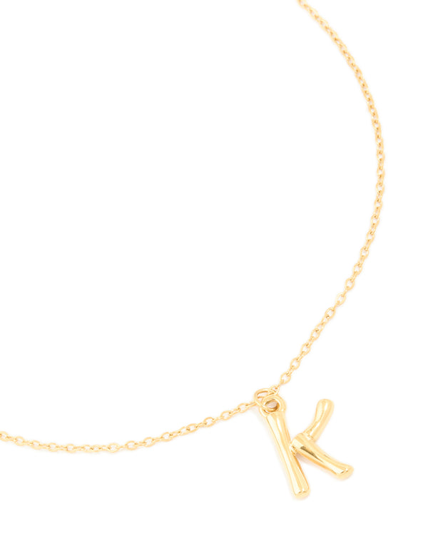 Featuring a waterproof bamboo letter K crafted from gold plated stainless steel initial pendant necklace close up view