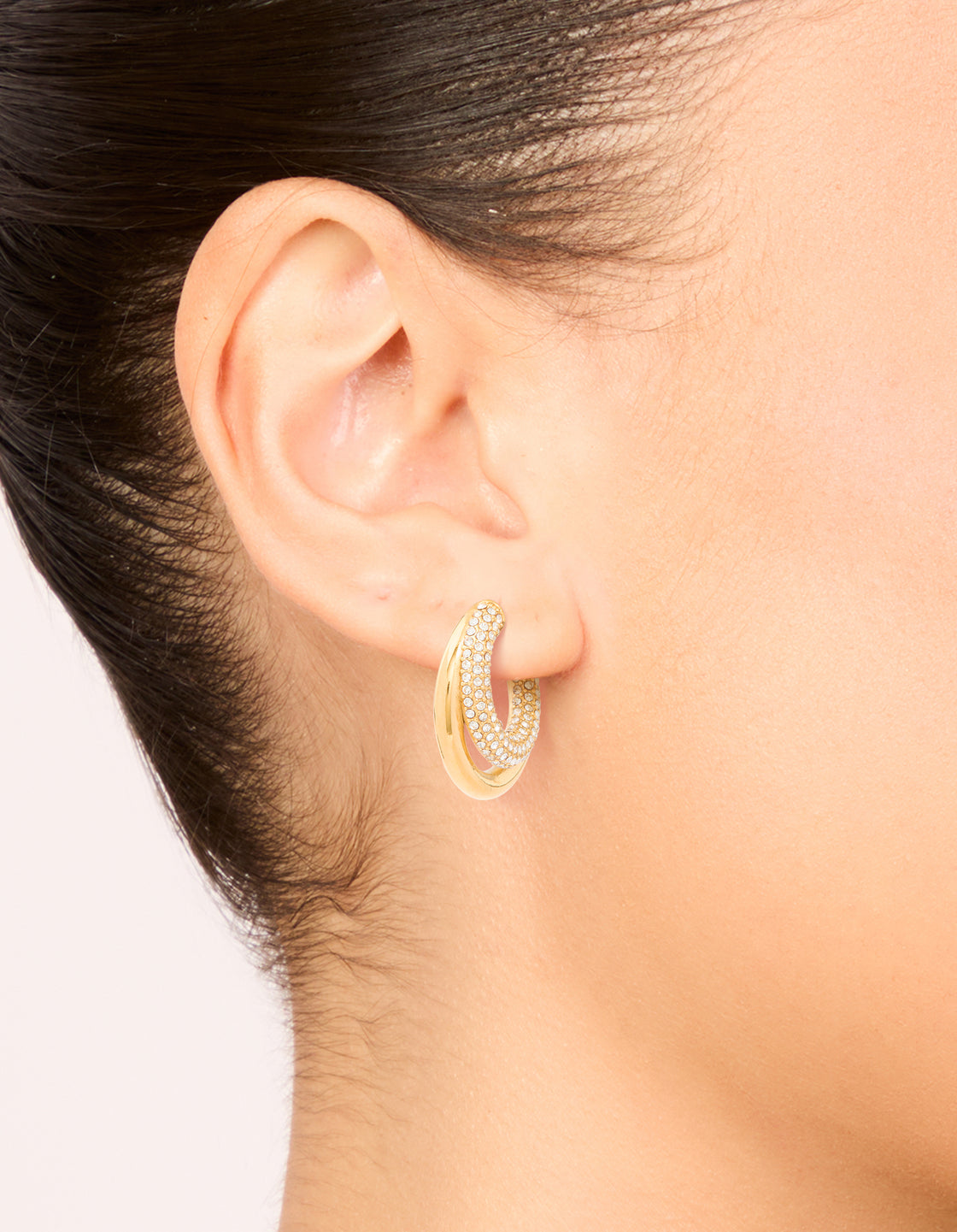 Featuring waterproof statement hoop earrings in gold plated stainless steel with cubic zirconia pave double large illusion design on ear view