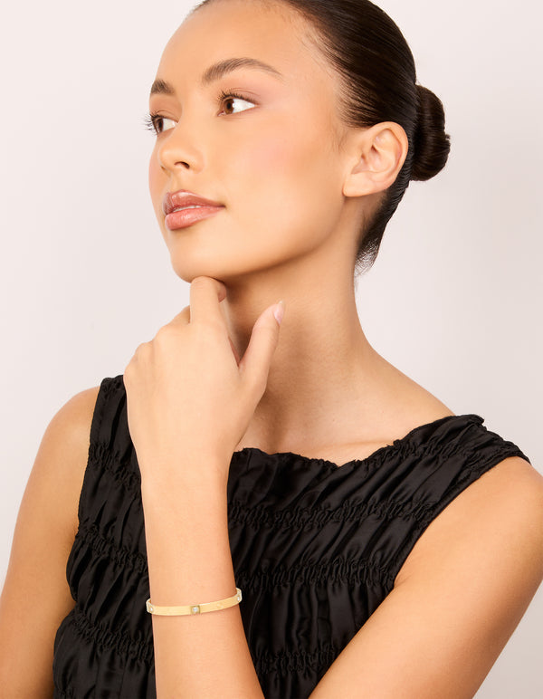 Crafted from waterproof gold plated stainless steel, this cubic zirconia flower bangle complements elegant styling on model view