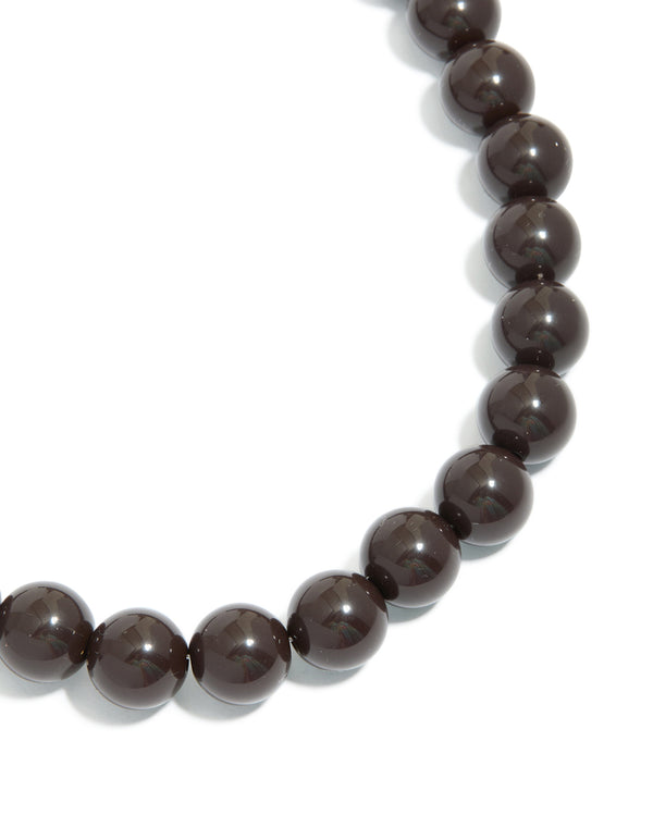 Showcasing a chocolate brown acrylic beaded necklace and gold accents close up view