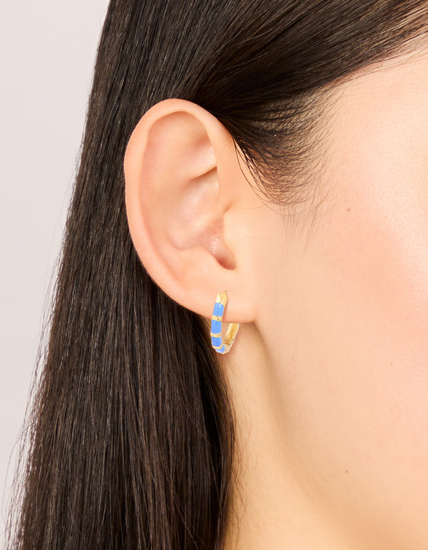 Showcasing waterproof statement huggie earrings crafted from stainless steel with bamboo design featuring blue enamel in a gold plated finish on ear view