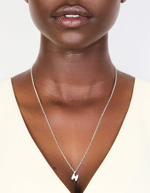 Discover this waterproof stainless steel mini bubble letter H necklace featuring initial pendant in dainty style silver on neck view