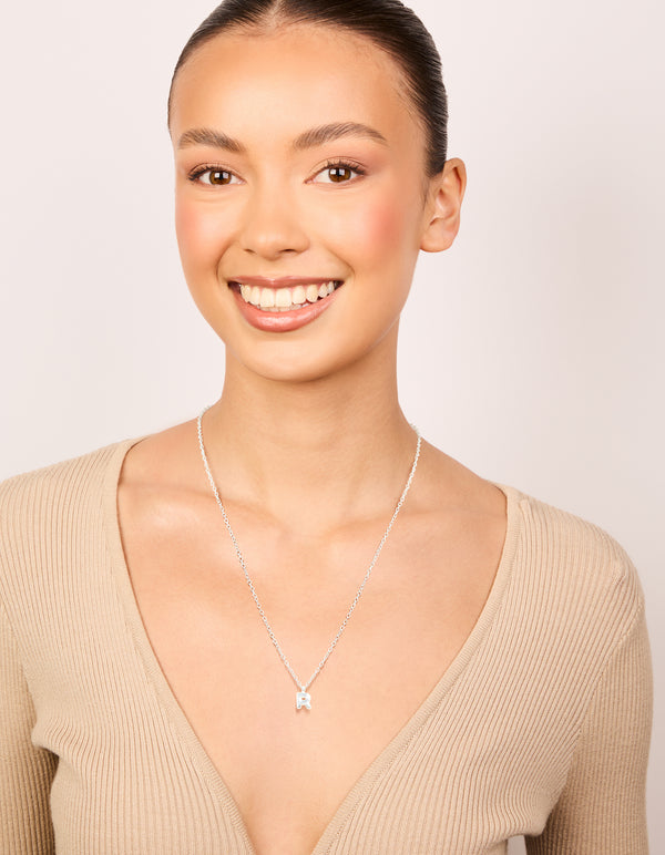Crafted from waterproof stainless steel mini bubble letter R necklace with initial pendant in silver and dainty styling on model view