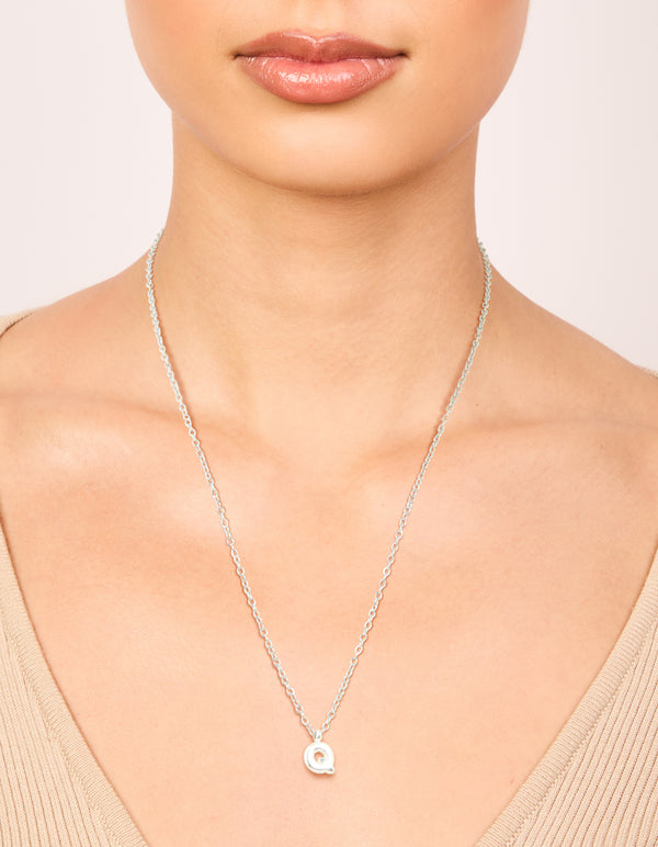 Designed with a waterproof stainless steel mini bubble letter Q necklace featuring initial charm pendant in silver on neck view
