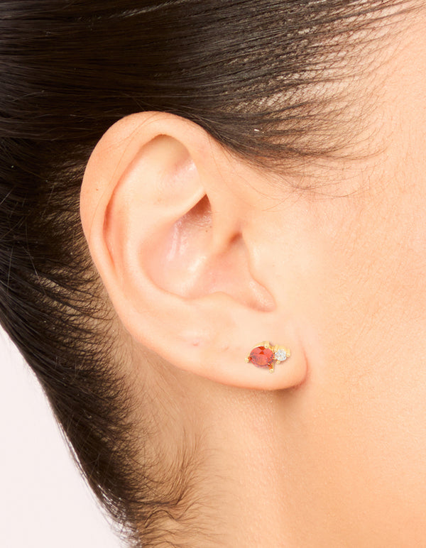 Highlighting waterproof stainless steel dainty stud earrings in coral and clear cubic zirconia stones in gold plated finish on ear view