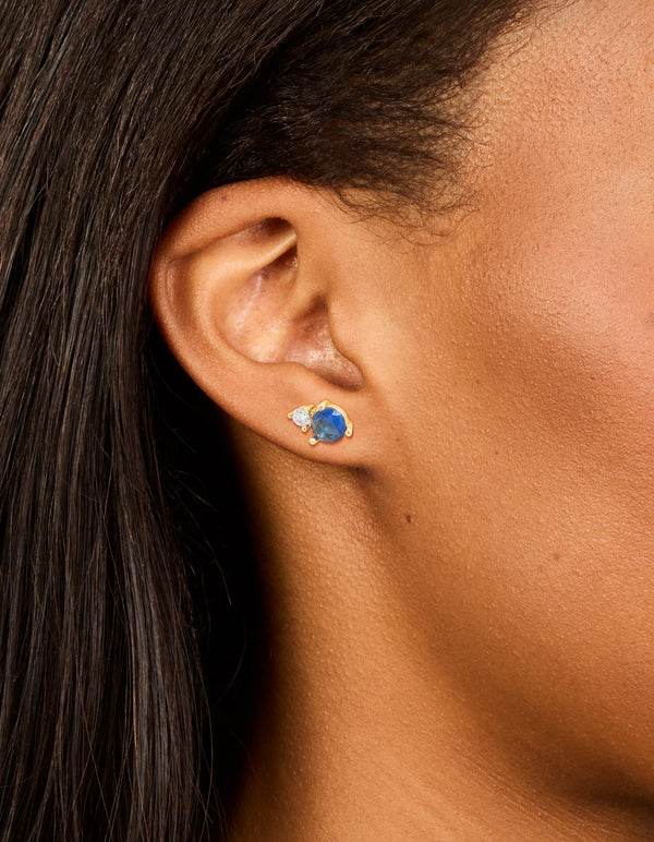 Waterproof gold plated stainless steel cubic zirconia duo September birthstone stud earrings in royal blue and clear on ear view