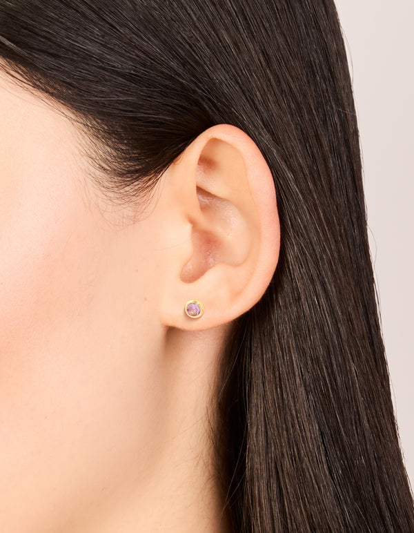 Delicate waterproof bezel set stud earrings with lavender cubic zirconia stones in gold plated stainless steel on ear view