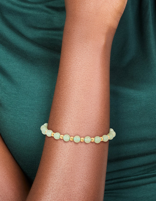 Featuring a waterproof beaded stretch bracelet in gold plated stainless steel with pale green beads on wrist view