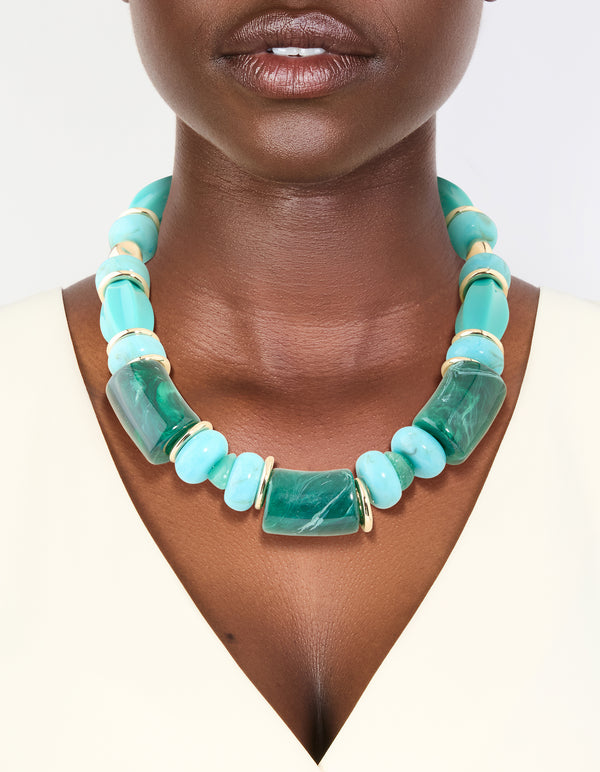 Featuring a chunky turquoise acrylic beaded necklace with square and round shapes in design on neck view