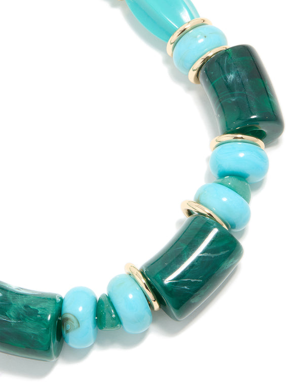 Showcasing an aqua acrylic beaded necklace with square and round turquoise elements accented by gold separators in close up view