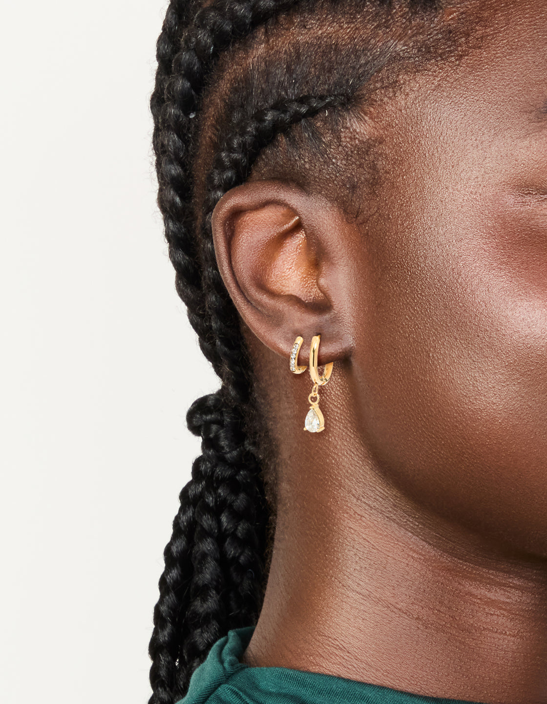 Showcasing waterproof gold plated stainless steel huggie earrings with featuring pear cut cubic zirconia in a 2-pack on ear view