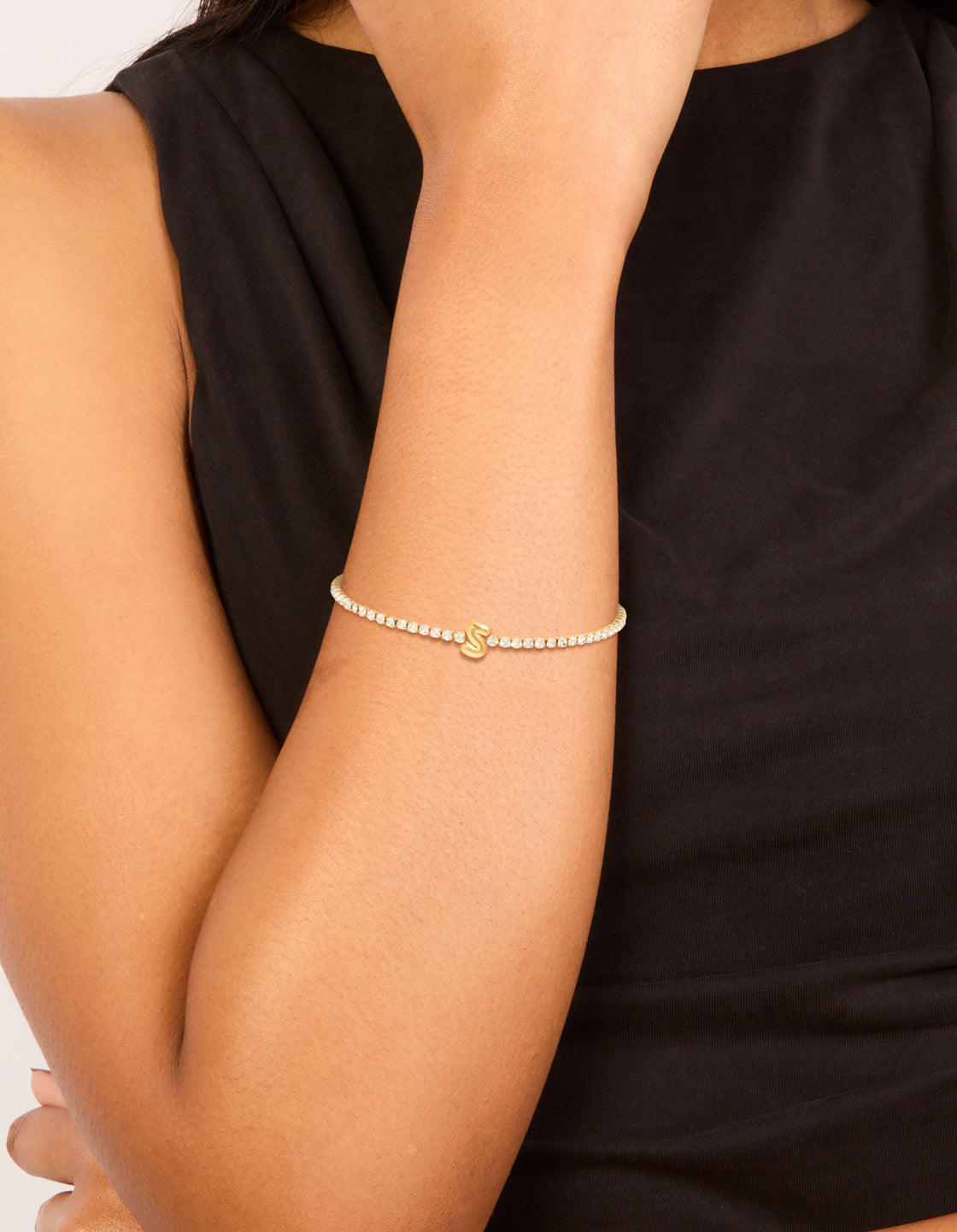 Showcasing a waterproof gold plated stainless steel cubic zirconia letter S tennis bracelet on wrist view