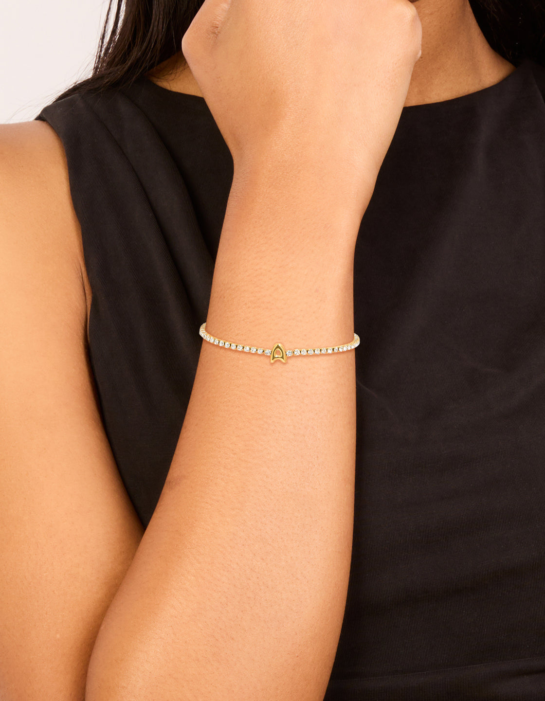 Showcasing a waterproof gold plated stainless steel tennis bracelet with cubic zirconia stones and letter A initial on wrist view