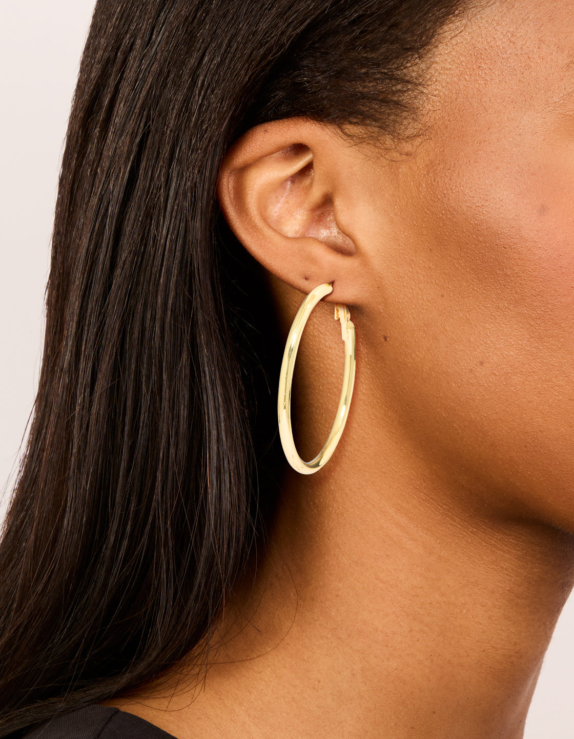 Showcasing gold plated thick hoop earrings with statement and chunky style on ear view