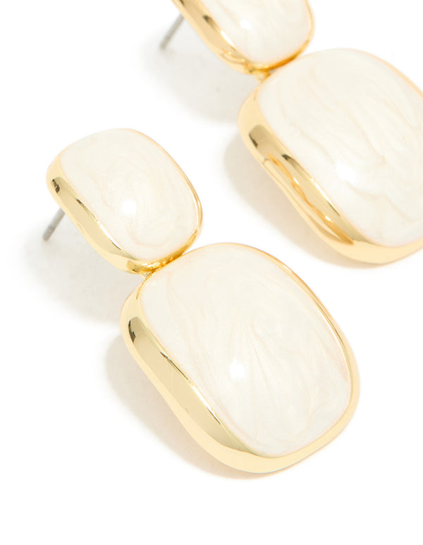 Featuring cream enamel and gold plated construction, statement drop earrings close up view