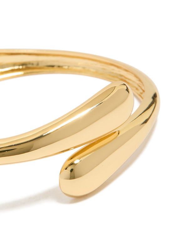 This gold plated open wrap hinged bangle highlights detailed craftsmanship in a close up view