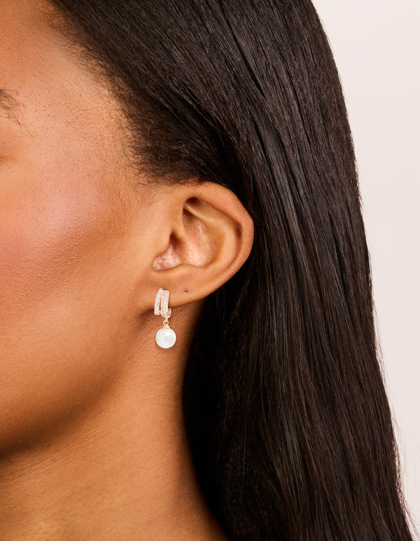 Displaying rose gold plated cubic zirconia illusion pearl drop earrings with hoop closure in ivory on ear view