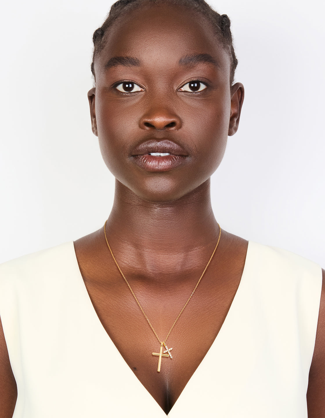 Designed with brass and gold plating, this double cubic zirconia cross necklace features charm pendants in statement style on model view