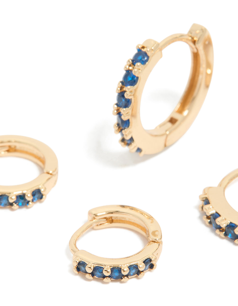 Designed with gold cubic zirconia huggie earrings featuring clear and sapphire stones in a 3-pack close up view